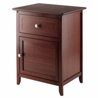 A dark wood nightstand or small cabinet with a top surface, a small drawer at the top and a larger cabinet door below, silver knobs on both the drawer and the door, and short legs.